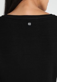 Maglione nero a maglia con scollatura ampia e tessuto texturizzato. Presenta una piccola etichetta argentata con la scritta "Esprit" sul retro.