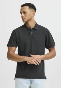 Svart polo-skjorte med korte ermene, tre-knaps placket og brodert logo. Laget av teksturert stoff, med sidespalter for komfort.