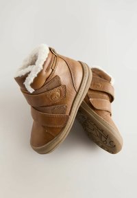 Braune Winterstiefel für Kleinkinder mit weißem Fleece-Futter, doppelten Klettverschluss-Riemen und einem Bären-Gesicht-Detail an der Seite, präsentiert vor einem schlichten Hintergrund.