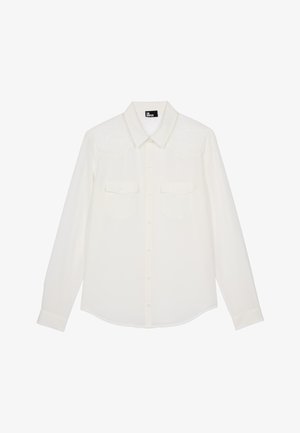 Camicia bianca a maniche lunghe con bottone frontale, due tasche sul petto e dettagli in pizzo sulle spalle; tessuto morbido con orlo curvo.