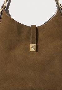 Brown suede hobo bag with a smooth, rounded shape. Features a vertical strap and a geometric gold-tone hardware accent.