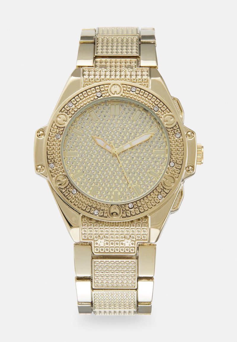 Gullur klokke med rund urskive, prydet med steiner, teksturert gullring og mønstret bezel. Klokken har luminerende visere og timemarkører.