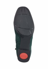 Scarpa da donna in suede verde con suola in gomma nera texturizzata. Presenta un'etichetta rossa "Tamaris Comfort" e un dettaglio con zip sul lato.