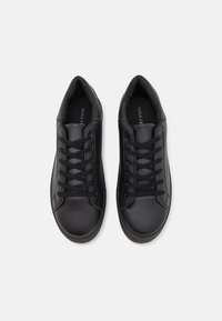 Sneaker neri realizzati in pelle sintetica. Le caratteristiche includono design con lacci, colletto imbottito e suola testurizzata per una migliore aderenza.