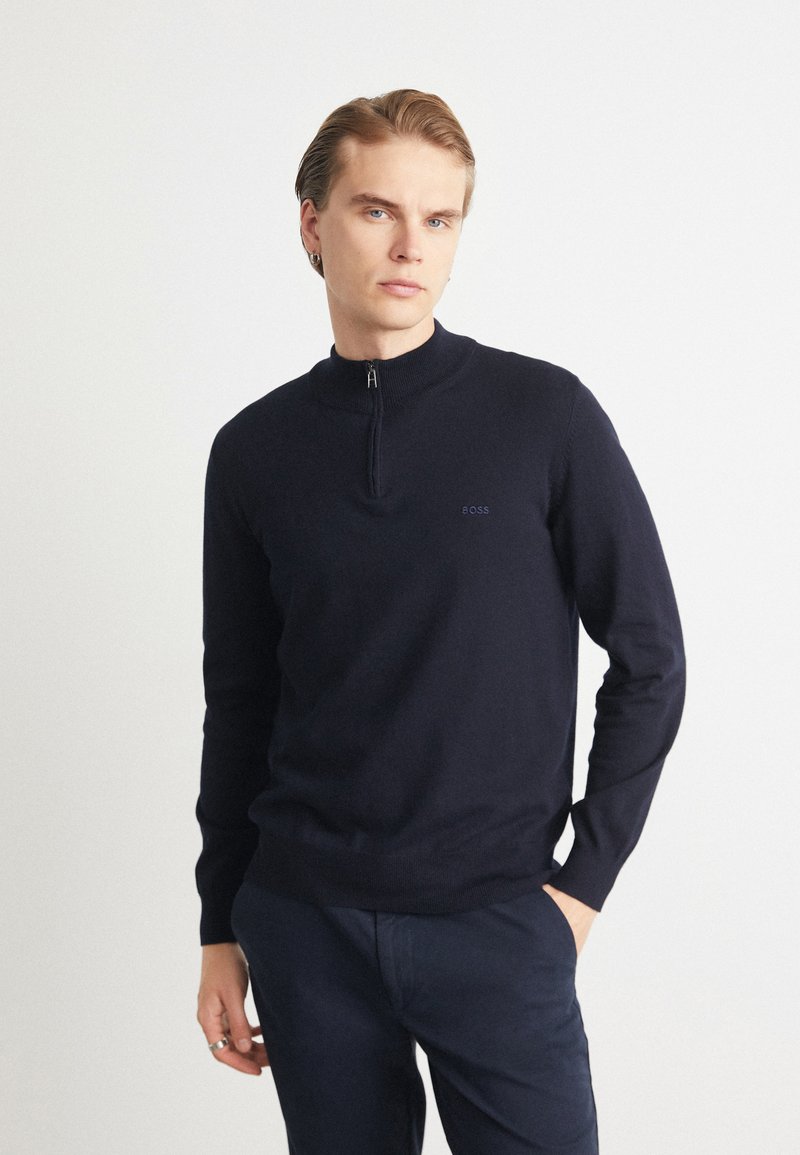 Marinblå zip-neck tröja i mjukt material, med en figursydd design och ribbade muddar. Diskret logotypdetalj på bröstet, tillsammans med marinblå byxor.