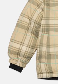 Beige og lysebrun ternet jakkeærme med lyseblå striber, elastisk manchet og en sidelomme med klap.