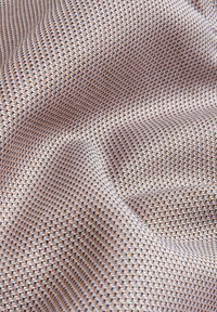 Textil med diamantmönstrad väv i beige och bruna nyanser, med en mjuk textur och subtil lyster.