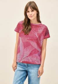 Camiseta de manga corta, color rosa claro, con un patrón floral y el texto "POSEE TU ENERGÍA" en blanco, hecha de una tela suave y transpirable.