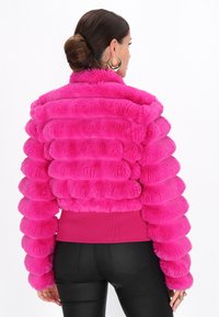 Faux fur pufferjakke i skarp pink med ribbet kant og runde, quiltede sektioner; har en høj krave.