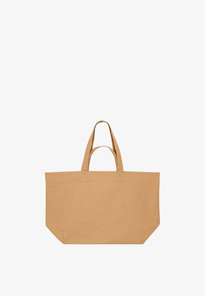 Grote rechthoekige beige canvas draagtas met twee korte handvatten en één lange handgreep, ontworpen om met de hand of over de schouder te dragen.
