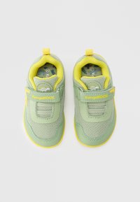 Παιδικά αθλητικά παπούτσια με πράσινο πλεγμένο ύφασμα και κίτρινα στοιχεία, με λάστιχο βέλκρο, επενδυμένο γιακά και υφασμένο πέλμα. Ορατή η επωνυμία KangaROOS.