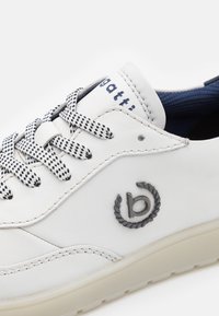 Białe skórzane sneakersy z granatowym wnętrzem, okrągłym logo, szachownicowymi sznurowadłami i teksturowaną podeszwą. Posiadają szwy i subtelne akcenty.