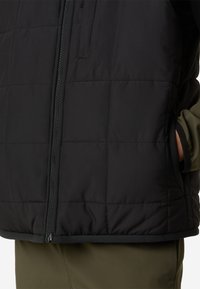 Fekete szigetelt kabát steppelt mintával, elülső cipzárral és két oldalzsebbel. Az alsó részen puha fekete szegéllyel díszítve.