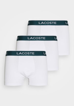 Hvite bomulls boxershorts med en mørkegrønn elastisk midjebånd med "LACOSTE"-logo. Solgt i et pakketilbud med tre.