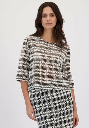 Top tricoté rayé noir et blanc avec des manches trois-quarts et un col rond ; tissu transparent avec des motifs floraux et géométriques.