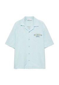 Chemise bleu clair à manches courtes avec col, texte brodé "AMAR COAST 1991" sur la poitrine gauche, et petit logo près du col.