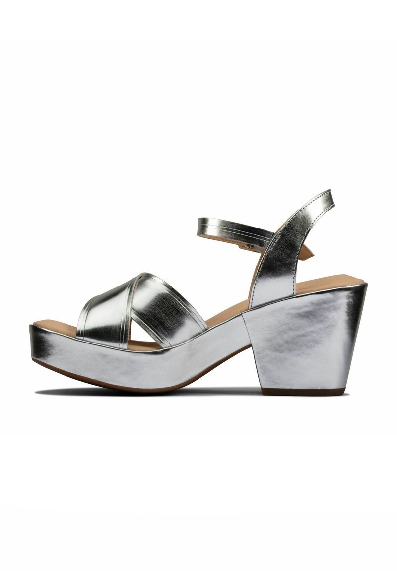 Sølvmetallic platform sandaler med åbne tæer og krydsede remme, med en kraftig hæl og glat tekstur.