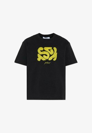 T-shirt nera in cotone con una grafica gialla testurizzata e testo stilizzato sulla parte frontale. Maniche corte, colletto a girocollo.
