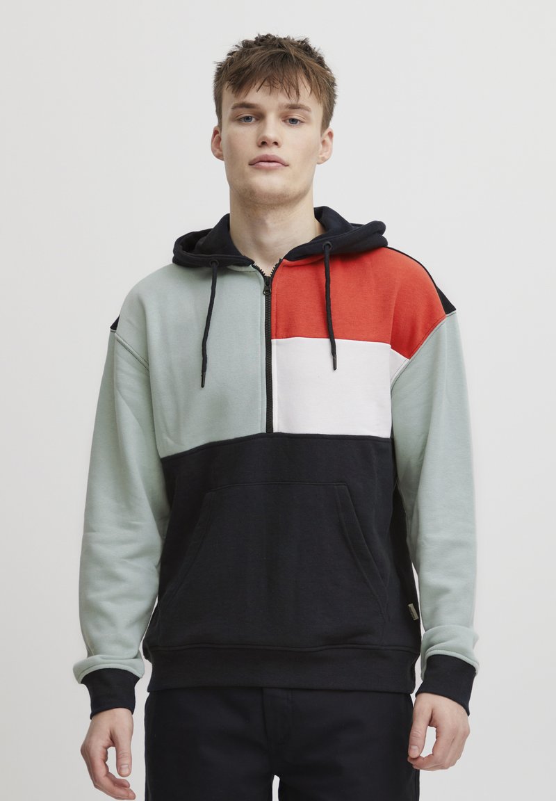 Felpa con cappuccio caratterizzata da una chiusura con zip, design a blocchi di colore in verde menta, rosso, bianco e nero; include tasca frontale e cordino.