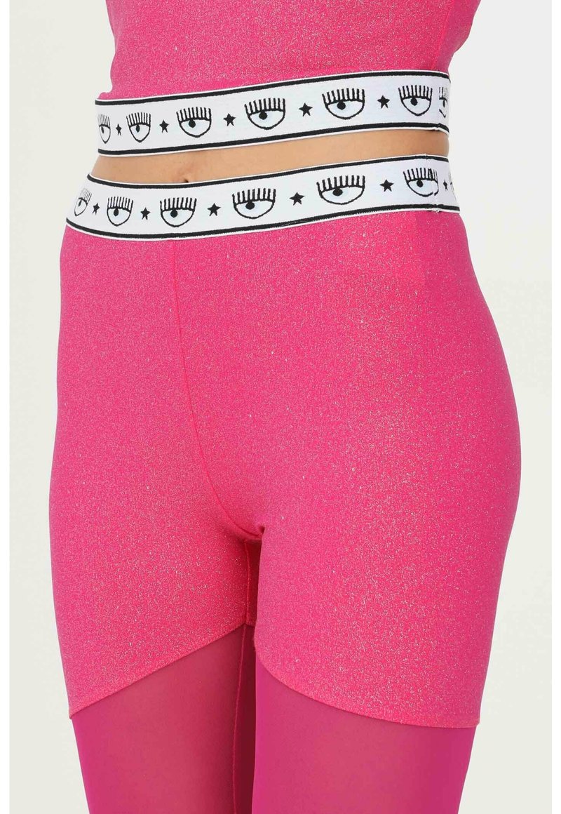Rosa metallische Shorts verfügen über einen breiten weißen Bund, der mit schwarzen Augen- und Sternmustern verziert ist, was ein gewagtes, kontrastierendes Detail schafft.