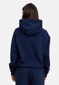 Navy blue hoodie with a drawstring hood, ribbed cuffs, and a relaxed fit. Fabric appears soft, with seams visible along the shoulders and back.