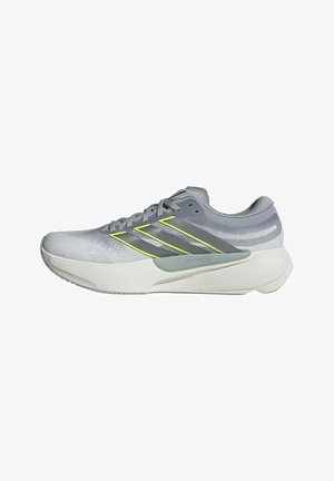 Chaussures de sport grises avec une tige en mesh, comportant trois bandes jaunes, une semelle blanche texturée et un design incurvé. Inscription notable "Guide Your Ride".