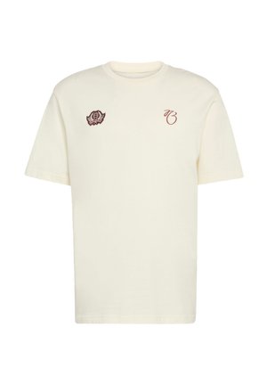 Μπλουζάκι από βαμβάκι σε κρεμ χρώμα με κοντά μανίκια και στρογγυλή λαιμόκοψη. Διαθέτει κεντημένες λεπτομέρειες στο αριστερό στήθος και κοντά στον ώμο.