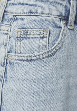 Jeans in denim azzurro chiaro con una piccola tasca posteriore con cuciture visibili e un rivetto metallico, che mostra una sottile texture sbiadita.