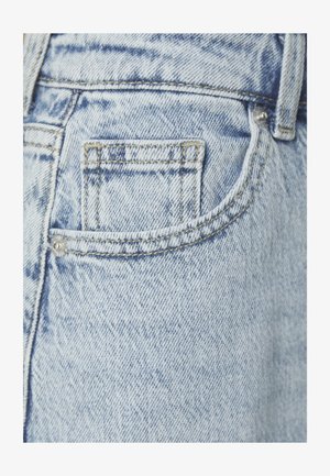 Light blue denim jeans featuring a small back pocket with visible stitching and a metal rivet, displaying a subtle faded texture.