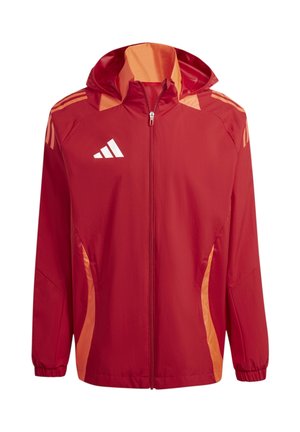 Giacca leggera rossa con accenti arancioni, chiusura a zip, cappuccio e tre strisce orizzontali su ciascun spalla. Logo del marchio riflettente sul petto.