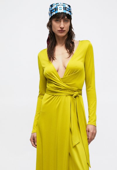 Rochie cu mâneci lungi, tip petrecută, din țesătură verde lime vibrant, cu decolteu adânc în V și detaliu nod la talie. Textură moale și siluetă fluidă.
