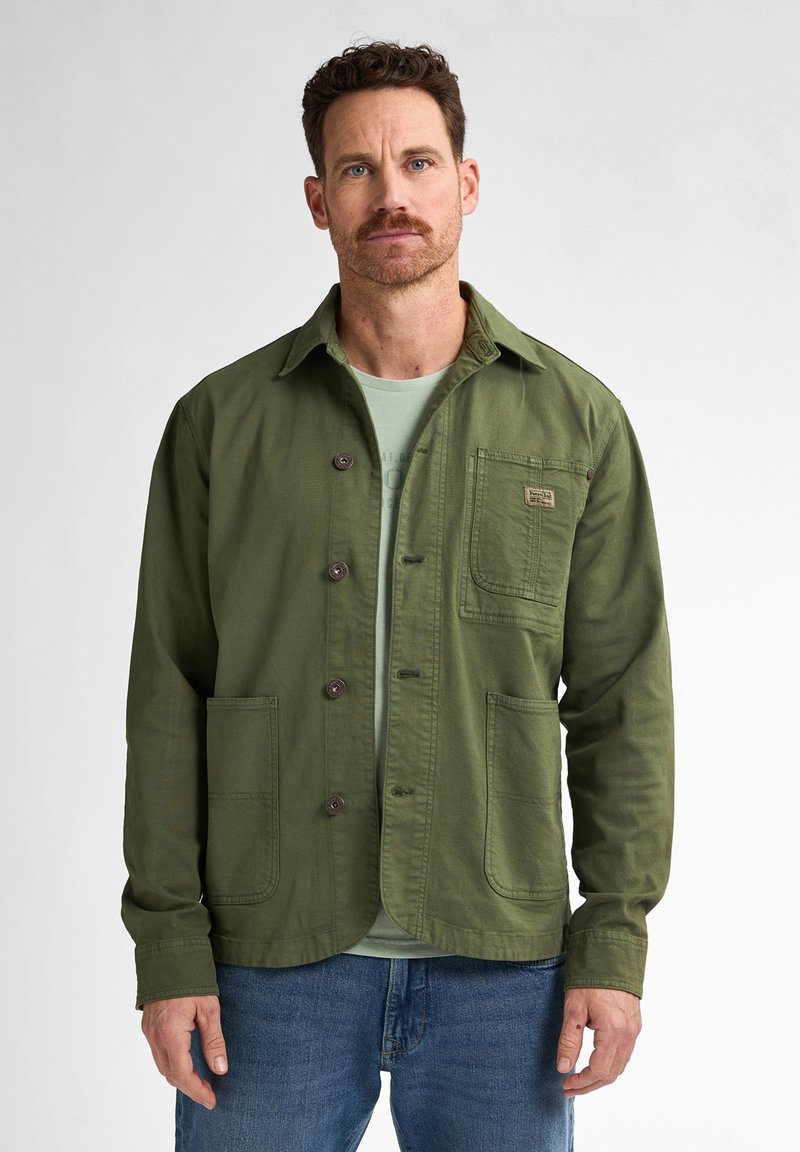 Green button-up jacket made of cotton, featuring a chest pocket, two front pockets, and a collar, paired with a light green shirt underneath.