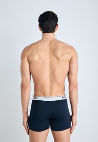 Navy boxer shorts with a white elastic waistband featuring the "BOSS" logo. The material appears smooth with a fitted design.