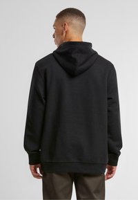 Black hoodie featuring a drawstring hood, ribbed cuffs, and hem. Made of soft fabric, it has a relaxed fit and a smooth texture.