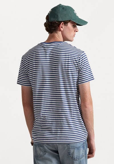 Triibuline T-särk sinise ja valgega, lühikesed varrukad, puuvillane kangas, ümmargune kaelus, mugava istuvuse ja sirge loodiga. Tagantvaates on näha kanga tekstuur.