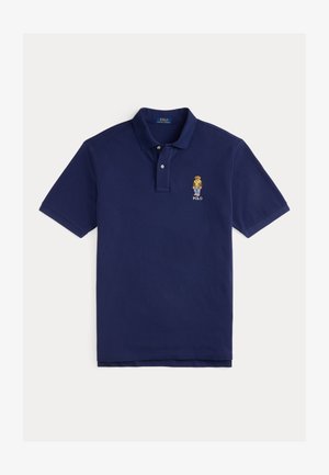 Polo azul-marinho feito de algodão, com colarinho, dois botões, mangas curtas e um pequeno logótipo bordado de um personagem no peito.
