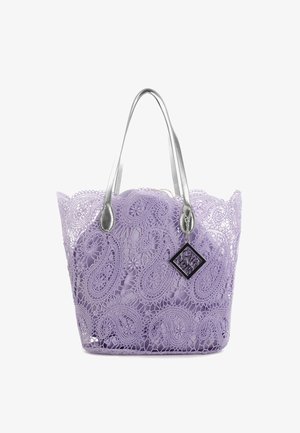 Sac fourre-tout en dentelle lilas à motif, avec des poignées métalliques argentées. Il présente un design paisley et une petite étiquette de marque noire.