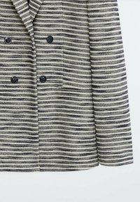 Dubbelknäppt jacka med horisontella svarta och beiga ränder, fyra svarta knappar och en enda framficka på höger sida.