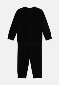 Black two-piece loungewear set featuring a long-sleeve top and matching pants. Soft fabric with ribbed cuffs and button detail at the neckline.
