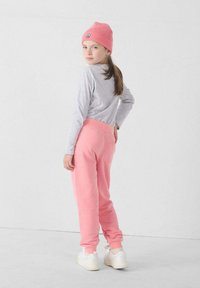 Roze sweatpants met een hoge tailleband, gecombineerd met een grijze langemouwen top en een roze gebreide beanie; gedragen met witte schoenen.