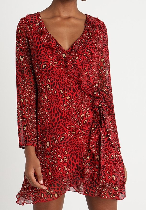 Robe portefeuille rouge avec un motif léopard, un col à volants, des manches longues et un ourlet flottant. Fabriquée en tissu léger et transparent.