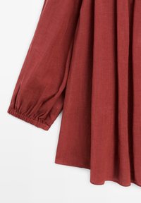 Reddish-brown long sleeve dress with gathered elastic cuffs and soft pleats on lightweight fabric.
