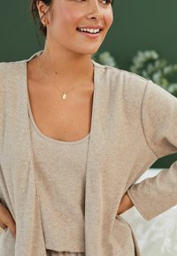 Beige, kevyt neulekartigan, joka on kerrostettu matching tank topin päälle. Yksinkertainen muotoilu, jossa on rento istuvuus ja hienovarainen rakenne. Kultaista riipusta sisältävä koru.