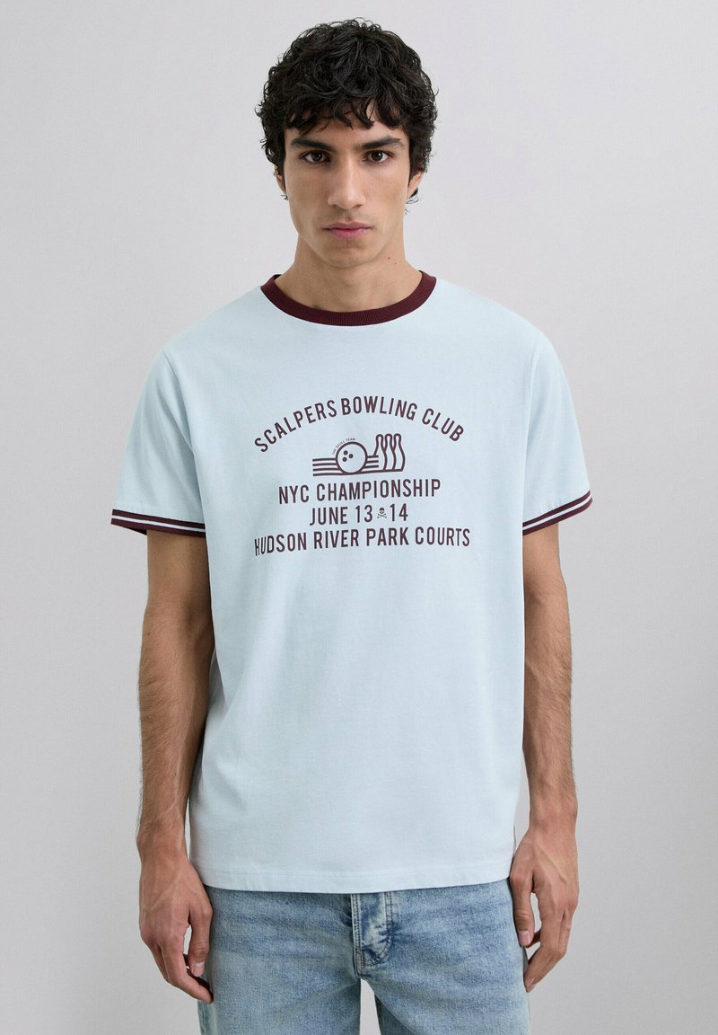 Camiseta de algodón azul claro con cuello y mangas de canalé burdeos. Presenta el logo "Scalpers Bowling Club" y un gráfico del Campeonato de NYC.