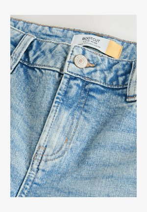 Bootcut jeans van lichtblauwe denim, met een lage taille, koperen stiksels en een metalen knoop met een logo. Zachte textuur en vervaagde afwerking.