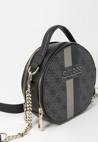 Borsa a tracolla rotonda nera con tessuto texture, hardware dorato e una striscia grigia. Presenta una maniglia superiore e una tracolla a catena per un facile trasporto.