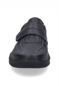 Zapato de cuero negro con cierre de velcro, punta redondeada, detalles de costura y suela duradera. Textura suave y diseño minimalista.