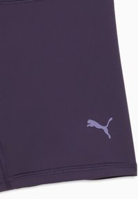 Κοντινό πλάνο σκούρων μοβ αθλητικών σορτς με μικρό ανοιχτό μοβ λογότυπο Puma στο κάτω δεξιό μέρος.