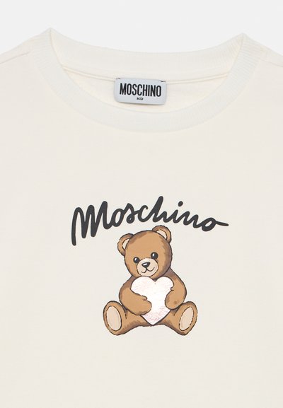 Sweatshirt bianco in cotone con un orsetto dei cartoni animati che tiene un cuore, con "Moschino" in grande lettering nero sopra la grafica dell'orsetto.