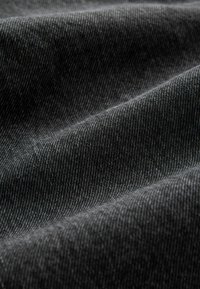 Texturovaná tmavě šedá látka s jemným diagonálním žebrovaním, vykazující měkké splývání a hladký povrch, typický pro denim.